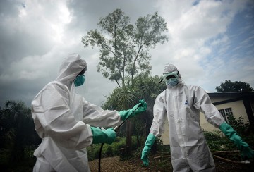 A group of young volunteers wears special uniform and wash their hands with chlorinated water ahead of sterilizing the bodies of people, died due to the Ebola virus, in Kenema, Sierra Leone on August 24, 2014. People work for 6 dollars per a day in burial and sterilizing works in Kenema where the infection of the virus is mostly seen. (Mohammed Elshamy/Anadolu Agency/Getty Images)